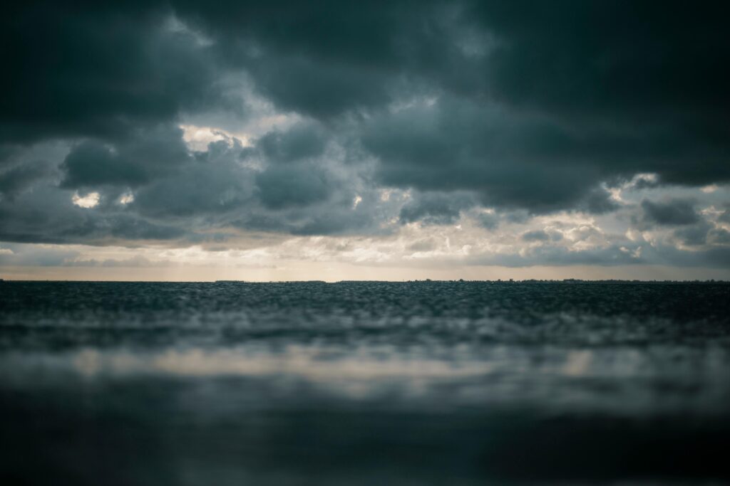 A captivating view of the ocean with dramatic dark clouds above, presenting a moody and dramatic seascape.